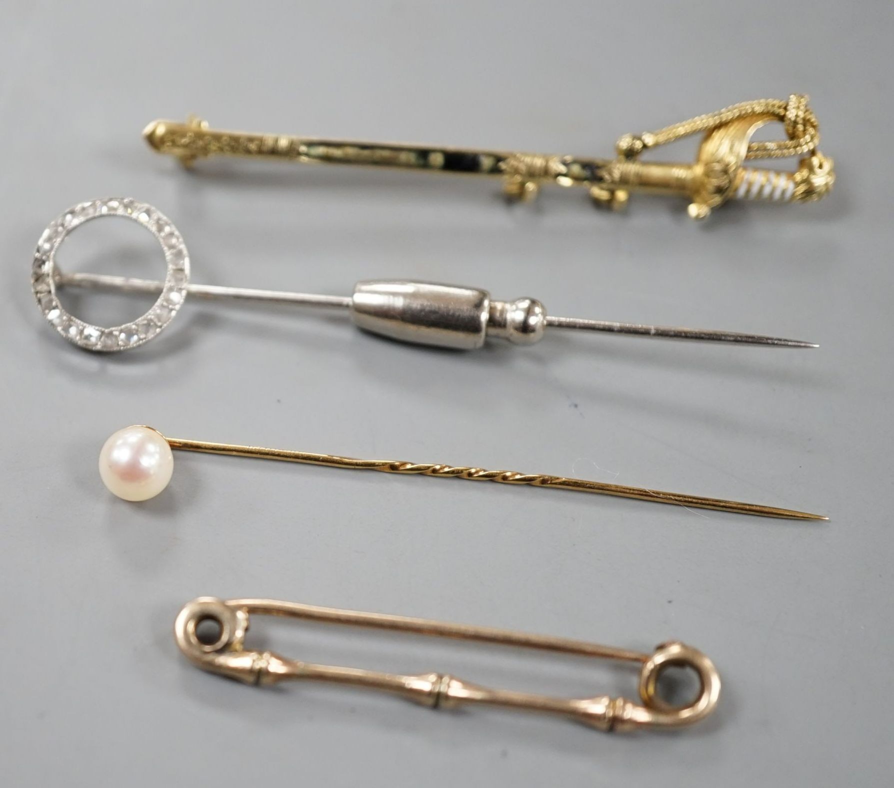A French white metal (poincon mark for platinum) and diamond set tie pin, 64mm, gross 3.4 grams, a 15ct and enamel(a.f.) sword brooch, gross 4.7 grams and toe 9ct pins, one with cultured pearl, gross 3 grams.